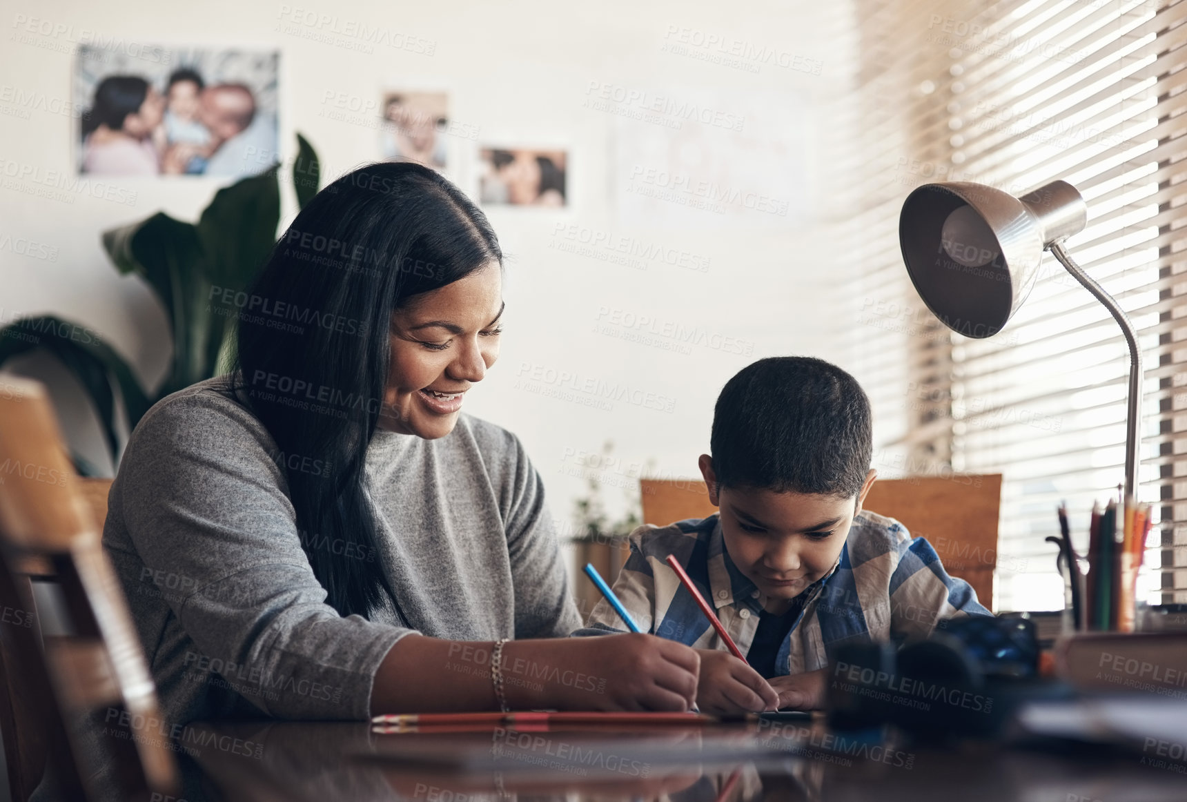 Buy stock photo Shot of an adorable little boy completing a school assignment with his mother at home