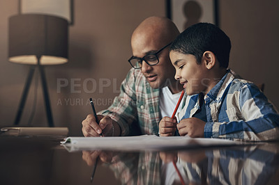 Buy stock photo Shot of an adorable little boy completing a school assignment with his father at home