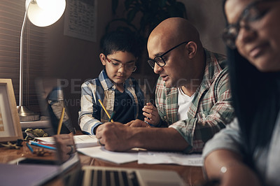 Buy stock photo Shot of an adorable little boy completing a school assignment with his father at home