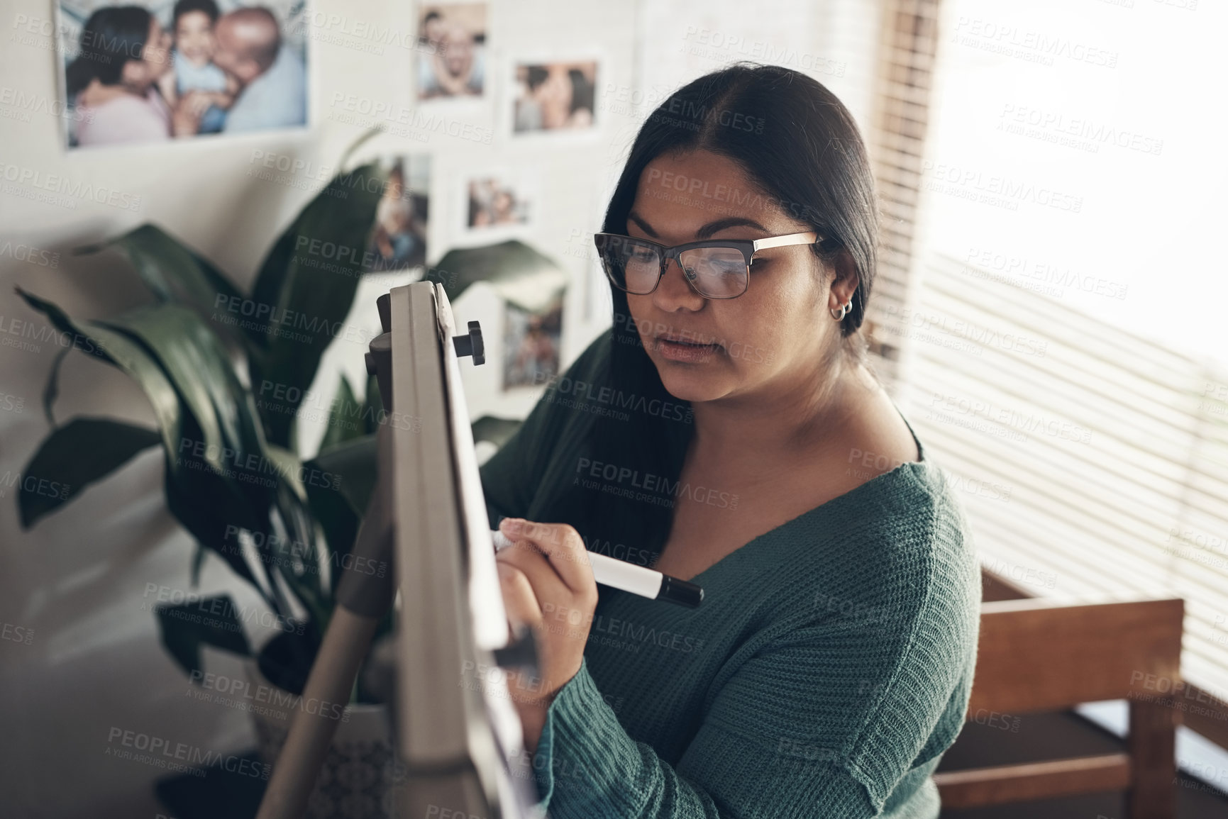 Buy stock photo Shot of a young woman using a whiteboard to teach a lesson from home