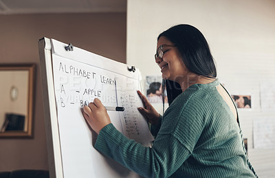 Buy stock photo Shot of a young woman using a whiteboard to teach a lesson from home