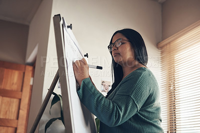 Buy stock photo Shot of a young woman using a whiteboard to teach a lesson from home