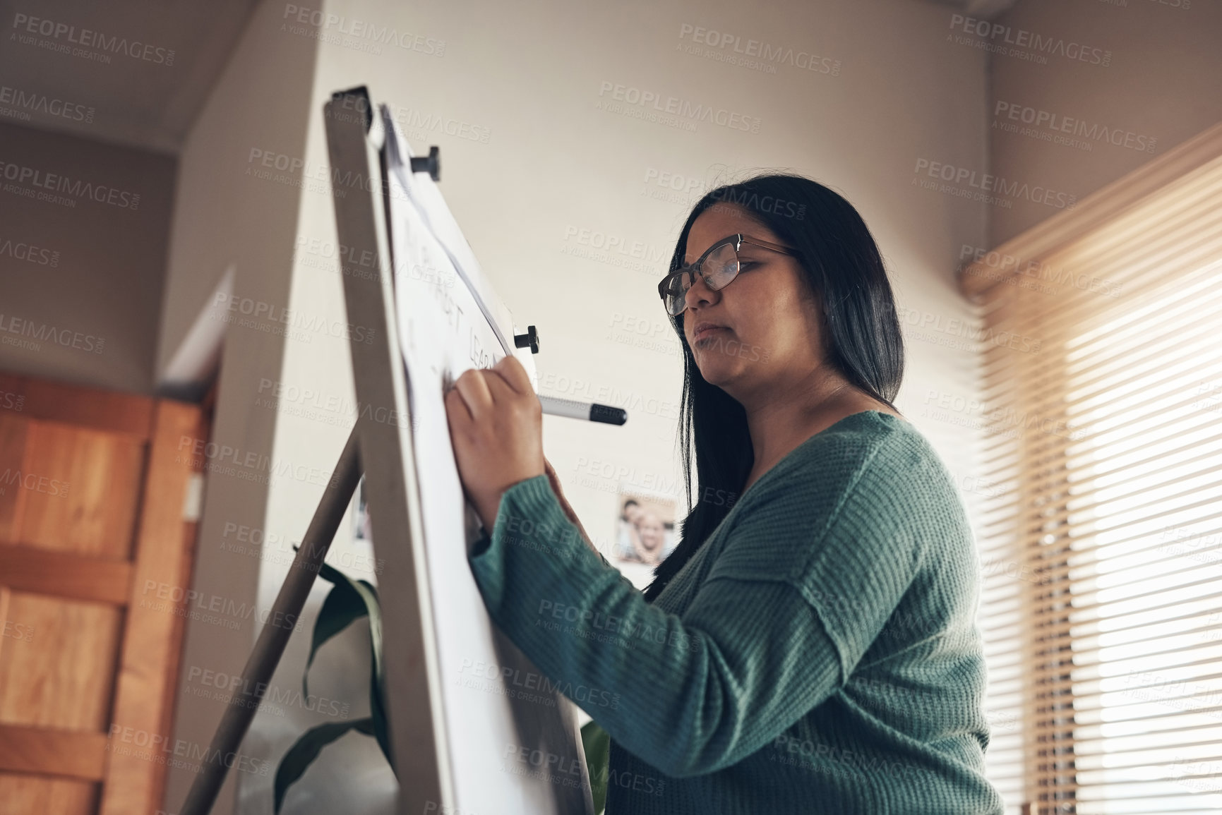 Buy stock photo Shot of a young woman using a whiteboard to teach a lesson from home