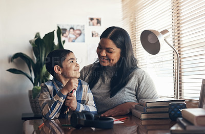 Buy stock photo Shot of an adorable little boy completing a school assignment with his mother at home