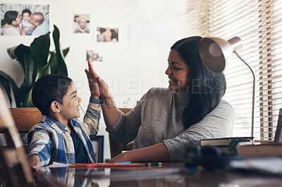 Buy stock photo Shot of an adorable little boy giving his mother a high five while completing a school assignment at home