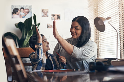 Buy stock photo Shot of an adorable little boy giving his mother a high five while completing a school assignment at home