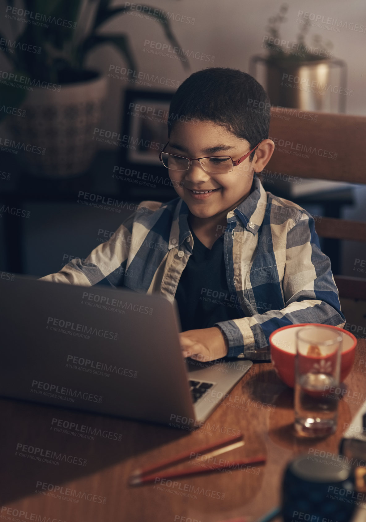 Buy stock photo Shot of an adorable little boy using a laptop while completing a school assignment at home