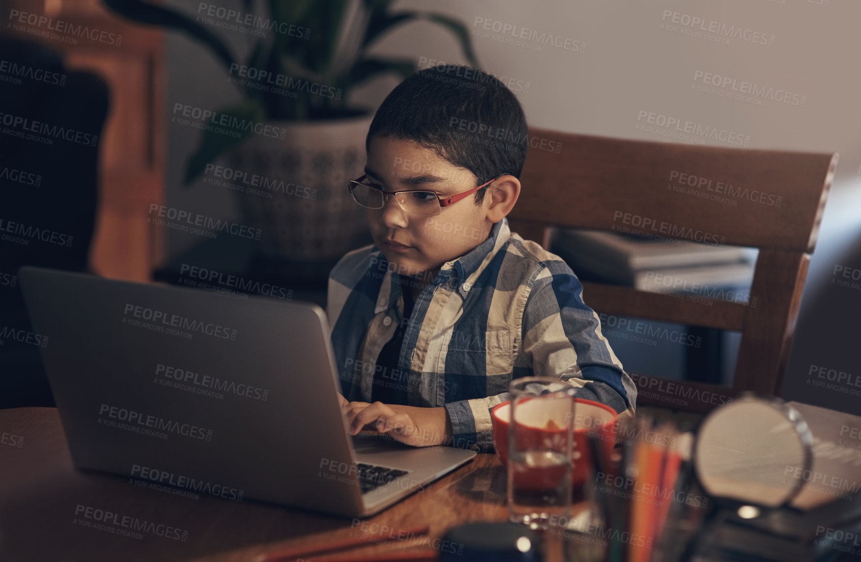 Buy stock photo Shot of an adorable little boy using a laptop while completing a school assignment at home