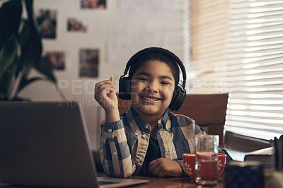 Buy stock photo Shot of an adorable little boy using a laptop and headphones while completing a school assignment at home