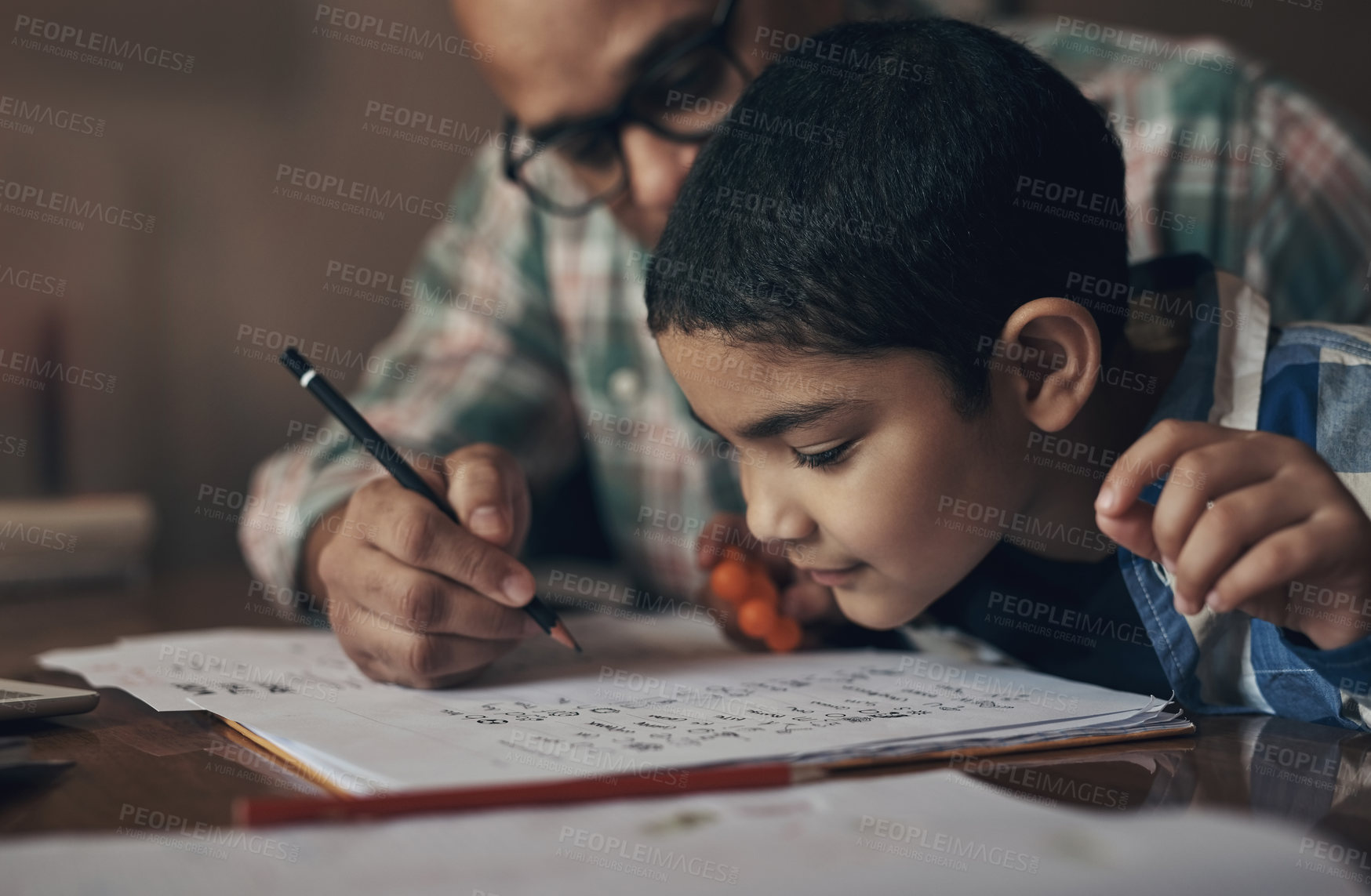 Buy stock photo Shot of an adorable little boy completing a school assignment with his father at home