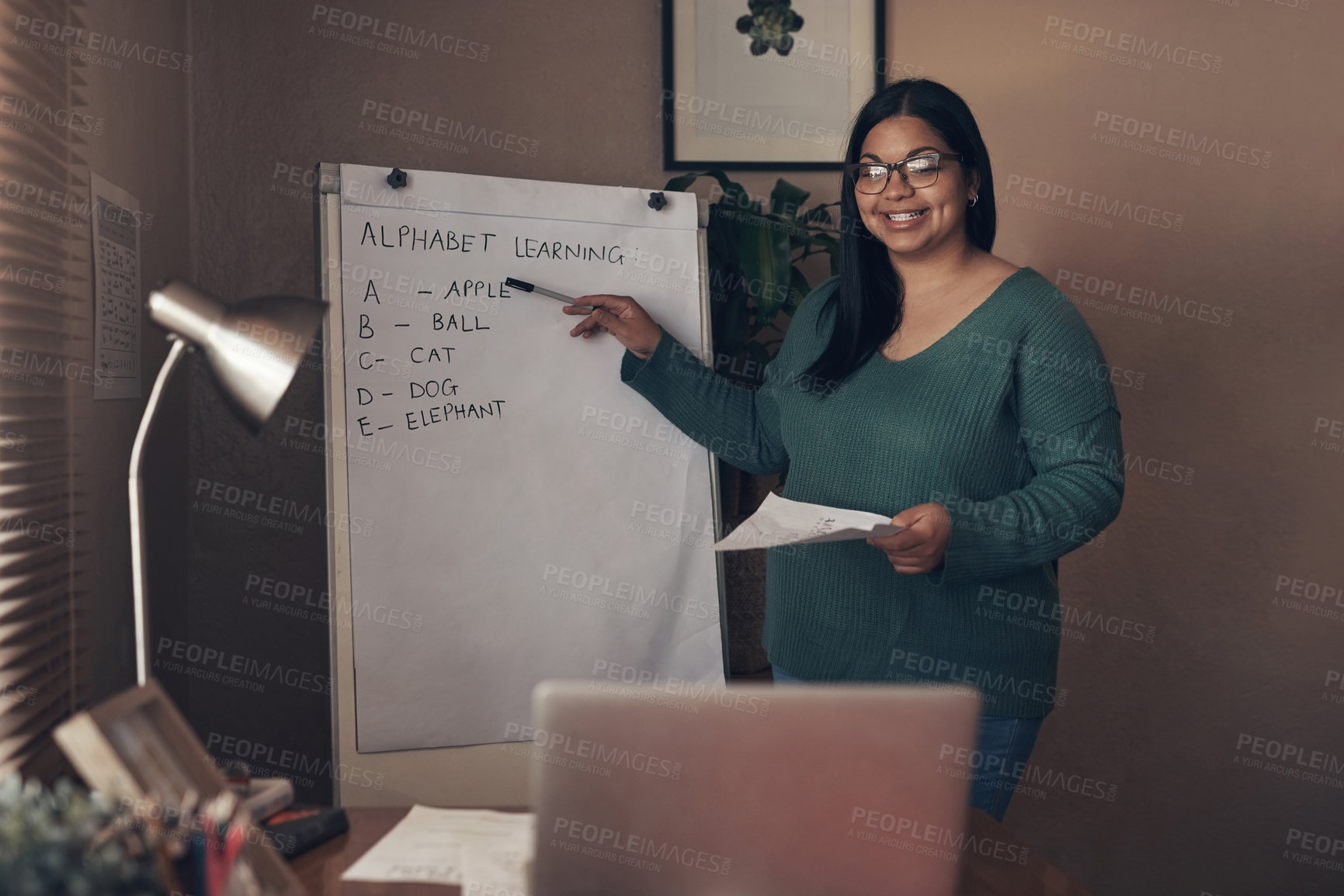 Buy stock photo Shot of a young woman using a laptop to teach a lesson from home