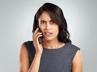 Buy stock photo Shot of a young woman talking on her cellphone while standing against a grey background