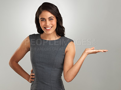 Buy stock photo Shot of a beautiful young woman gesturing towards copy space  against a grey background