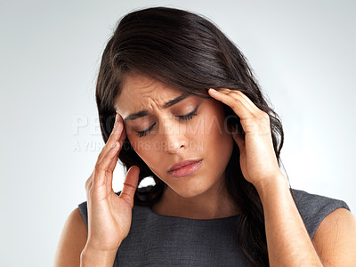 Buy stock photo Shot of a young woman suffering from a headache while standing against a white background