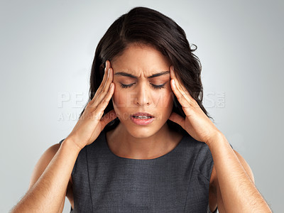 Buy stock photo Shot of a young woman suffering from a headache while standing against a white background