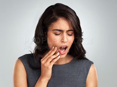 Buy stock photo Cropped shot of a young woman suffering from a toothache while standing against a grey background