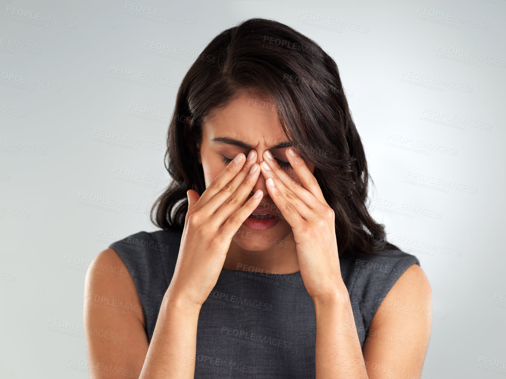 Buy stock photo Cropped shot of a young woman looking upset while standing against a grey background