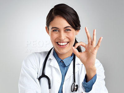 Buy stock photo Studio portrait of a young doctor showing an okay gesture against a grey background