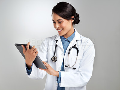 Buy stock photo Studio shot of a young doctor using a digital tablet against a grey background