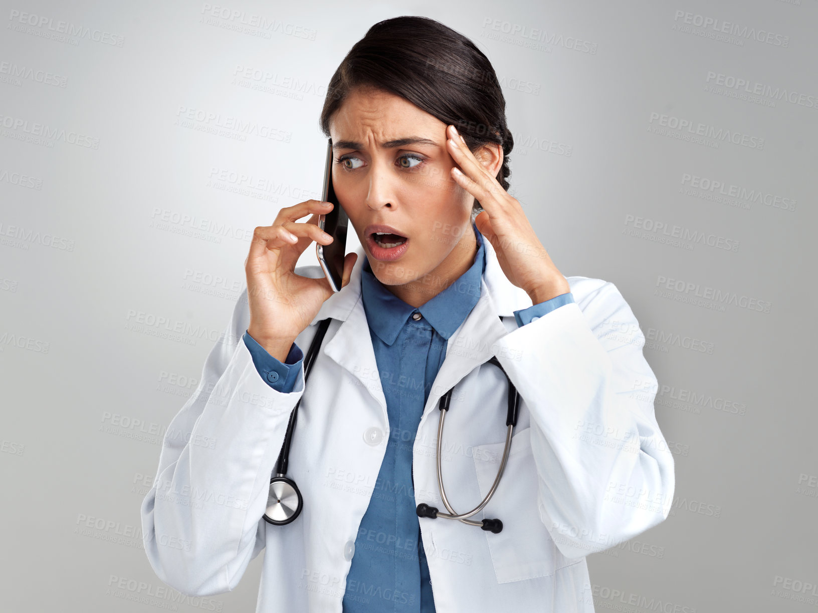 Buy stock photo Studio shot of a young doctor looking stressed while using a smartphone against a grey background