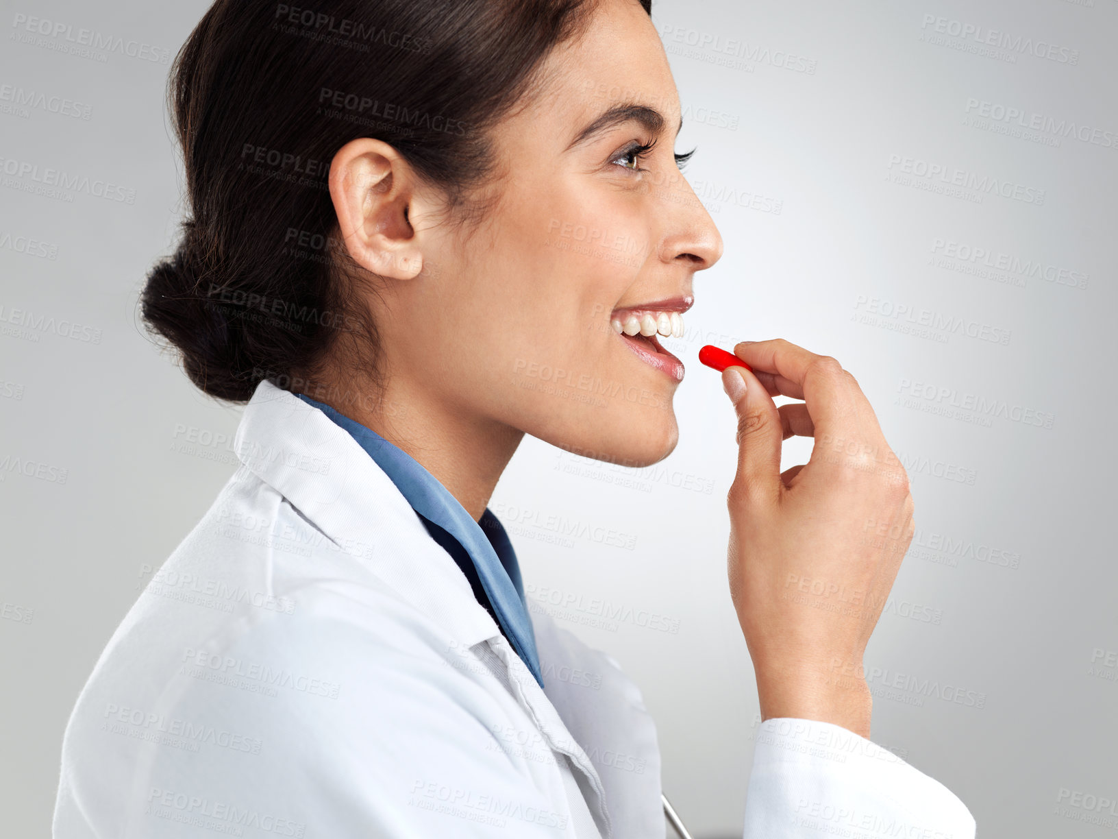 Buy stock photo Studio shot of a young doctor taking medication against a grey background