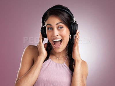 Buy stock photo Shot of a beautiful young woman looking surprised while holding her headphones against her head against a pink background