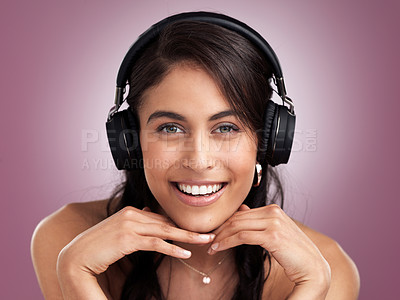 Buy stock photo Shot of a beautiful young smiling woman with her hands rested on her chin while wearing headphones against a pink background