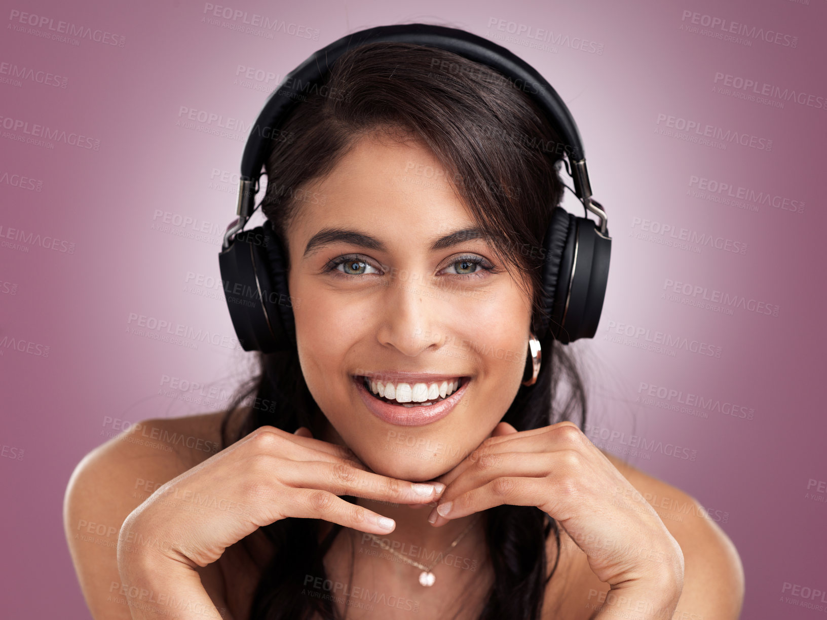 Buy stock photo Shot of a beautiful young smiling woman with her hands rested on her chin while wearing headphones against a pink background