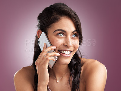 Buy stock photo Shot of a beautiful young woman smiling while talking on a mobile phone against a pink background