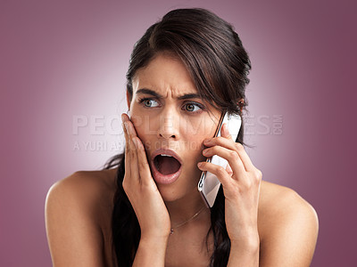 Buy stock photo Shot of a beautiful young woman looking shocked with her hand against her cheek while talking on a mobile phone against a pink background