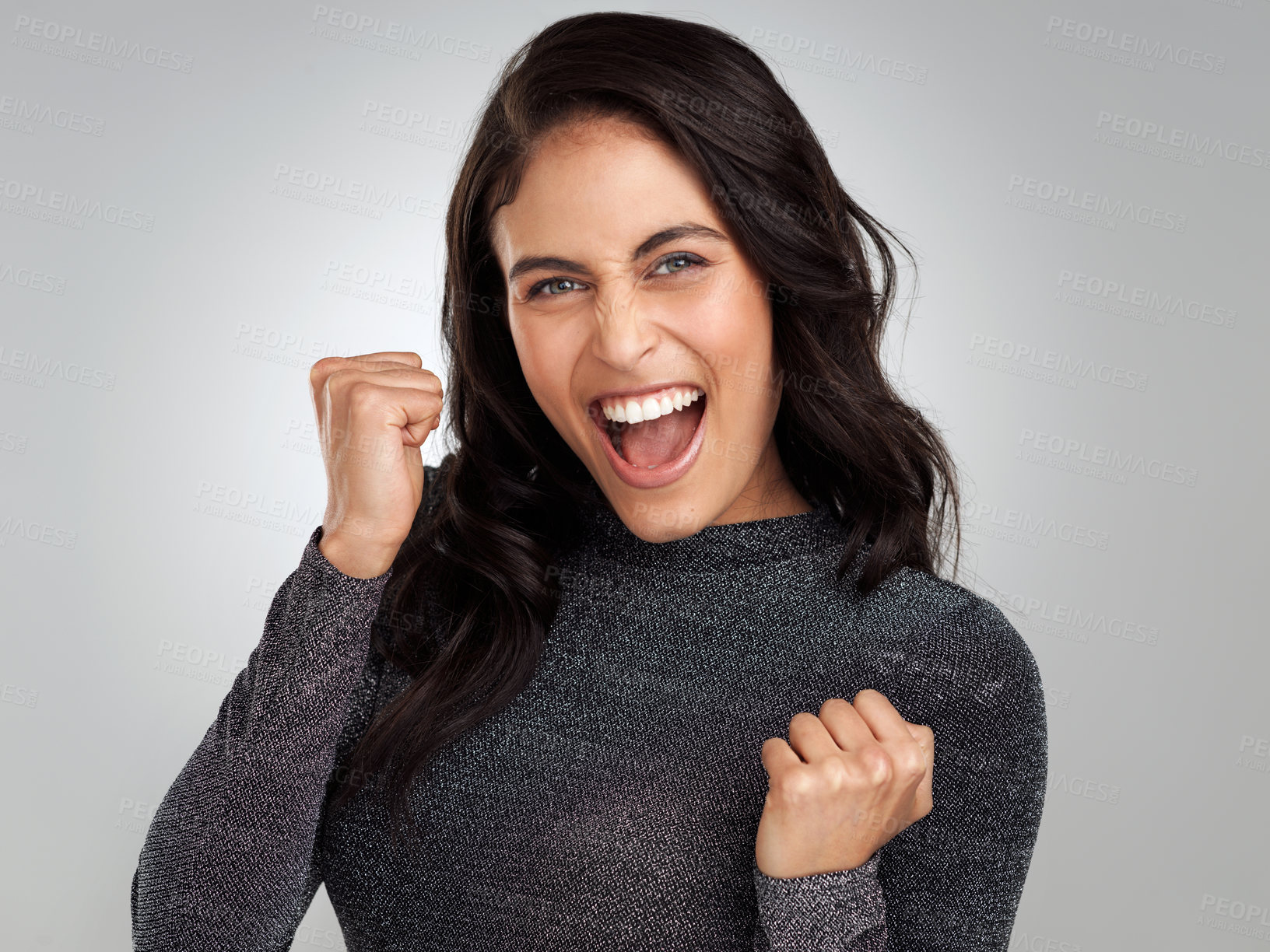 Buy stock photo Shot of a young woman looking cheerful while standing against a grey background