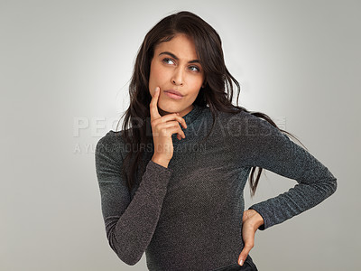 Buy stock photo Shot of a beautiful young woman looking thoughtful while standing against a white background