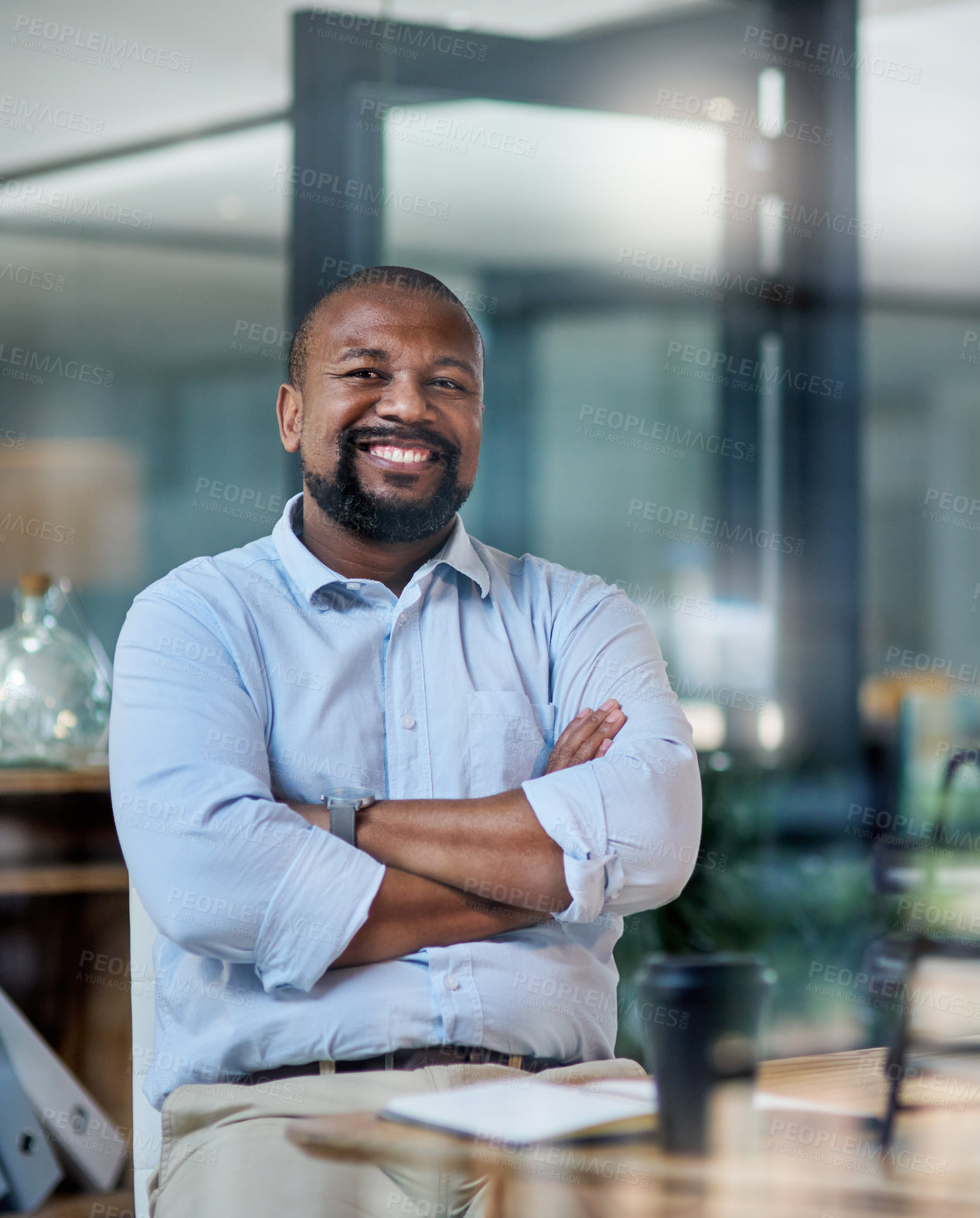 Buy stock photo Cropped portrait of a handsome mature businessman sitting alone in his office at night with his arms folded