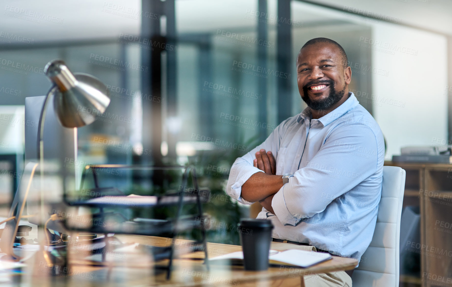 Buy stock photo Cropped portrait of a handsome mature businessman sitting alone in his office at night with his arms folded