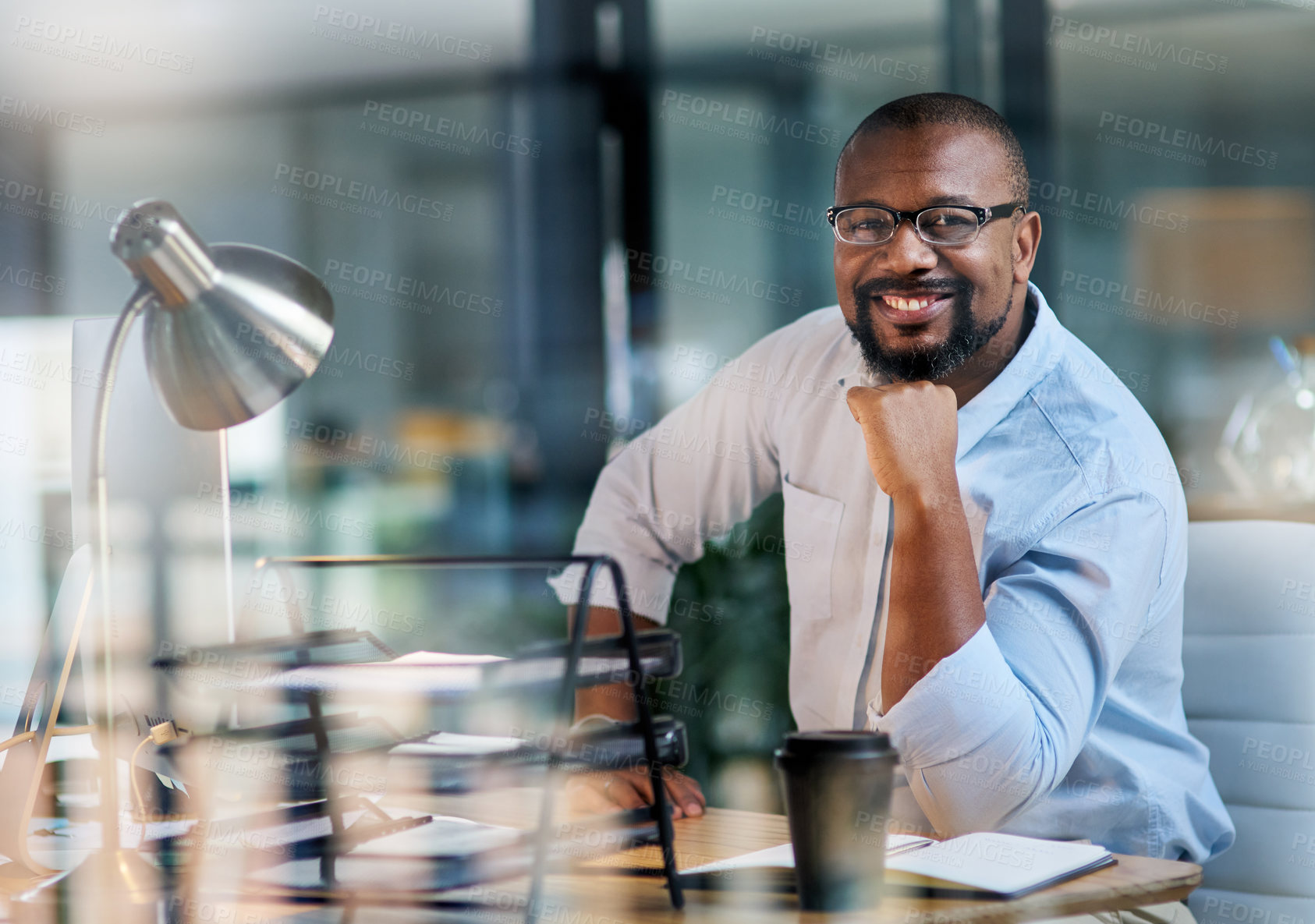 Buy stock photo Cropped portrait of a handsome mature businessman sitting alone in his office at night with his hand on his chin