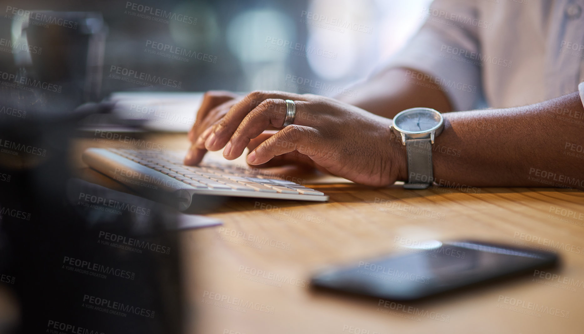 Buy stock photo Cropped shot of an unrecognizable businessman sitting alone at his office desk at night and typing on his keyboard