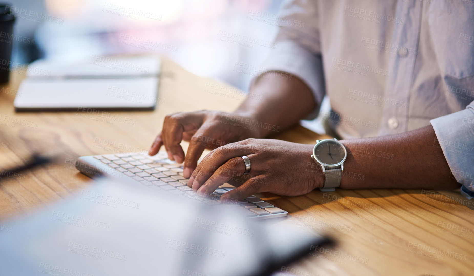 Buy stock photo Cropped shot of an unrecognizable businessman sitting alone at his office desk at night and typing on his keyboard