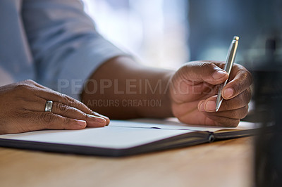 Buy stock photo Cropped shot of an unrecognizable businessman sitting alone at his office desk at night and writing in a notebook