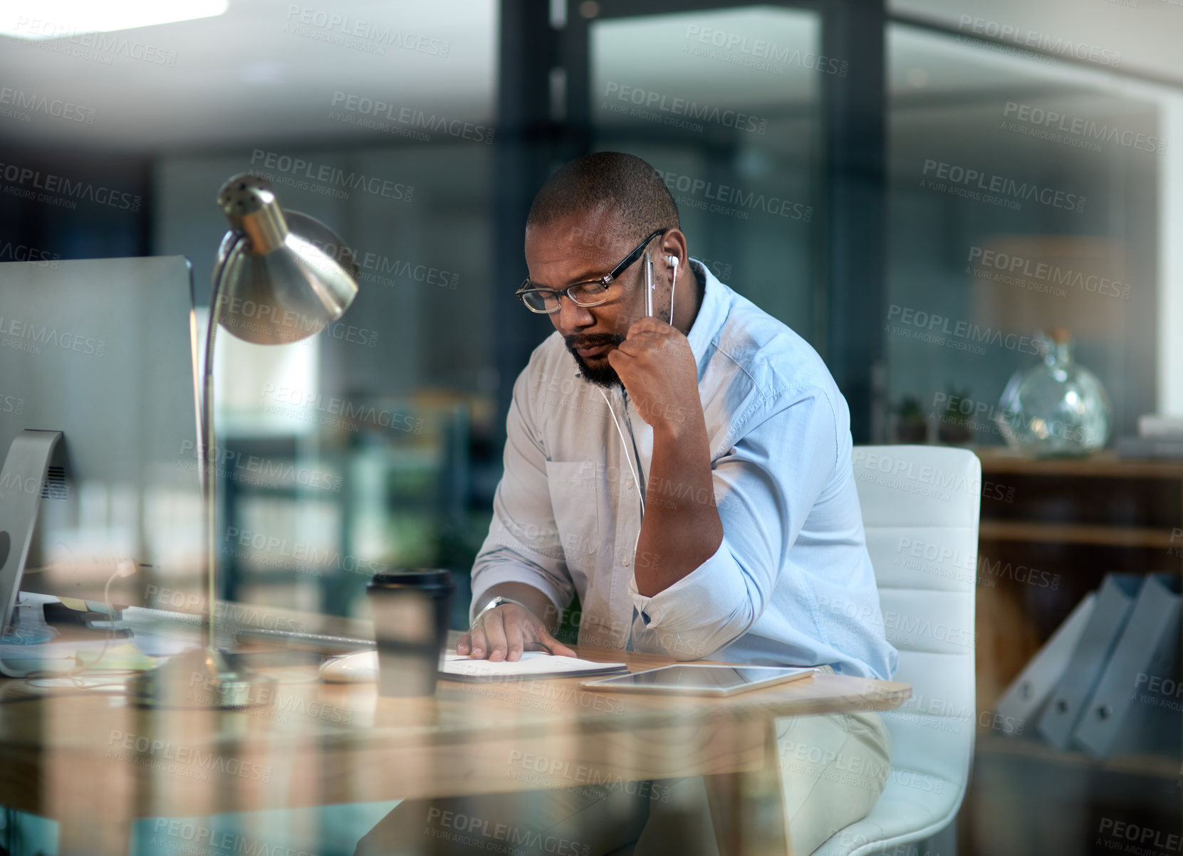 Buy stock photo Cropped shot of a mature businessman sitting in his office at night and looking contemplative while wearing earphones