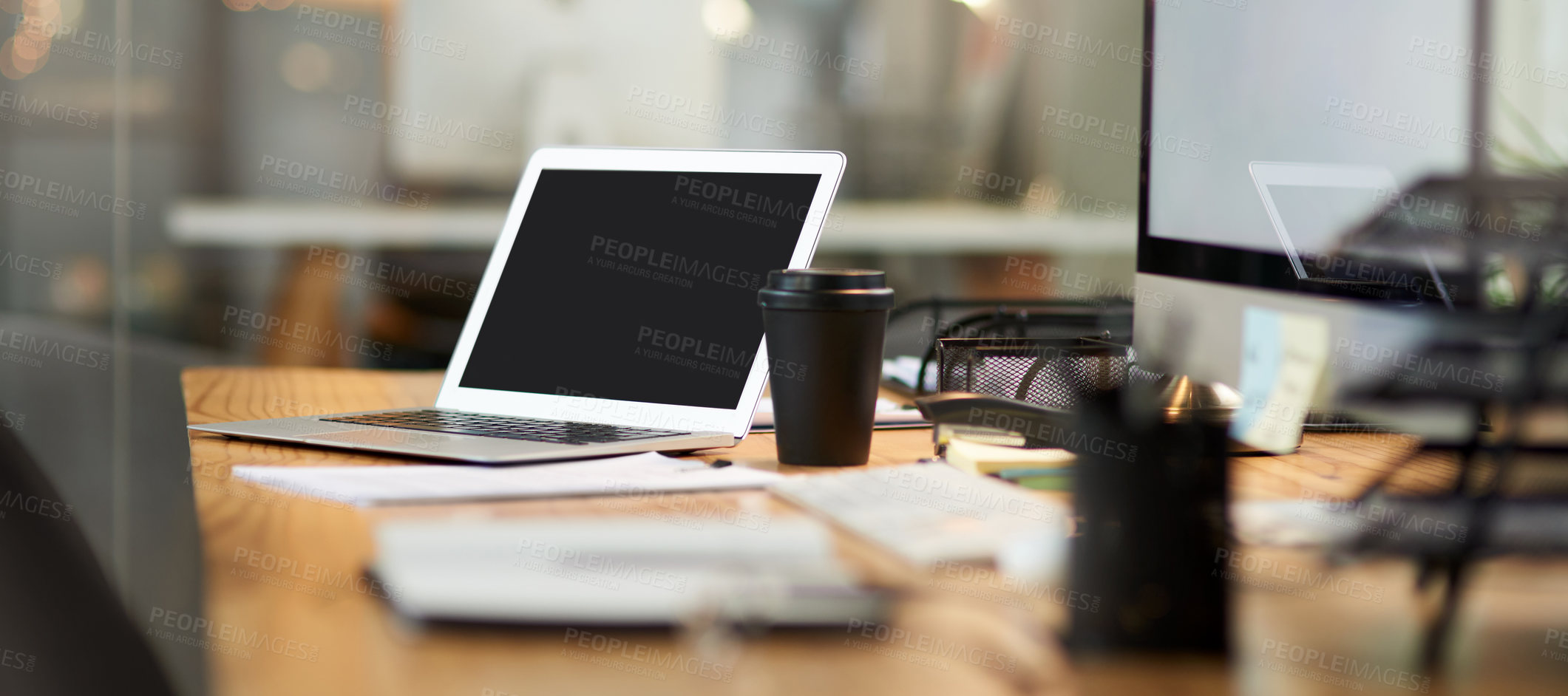 Buy stock photo Cropped shot of an office workstation scattered with stationery and technology during the late hours of the evening