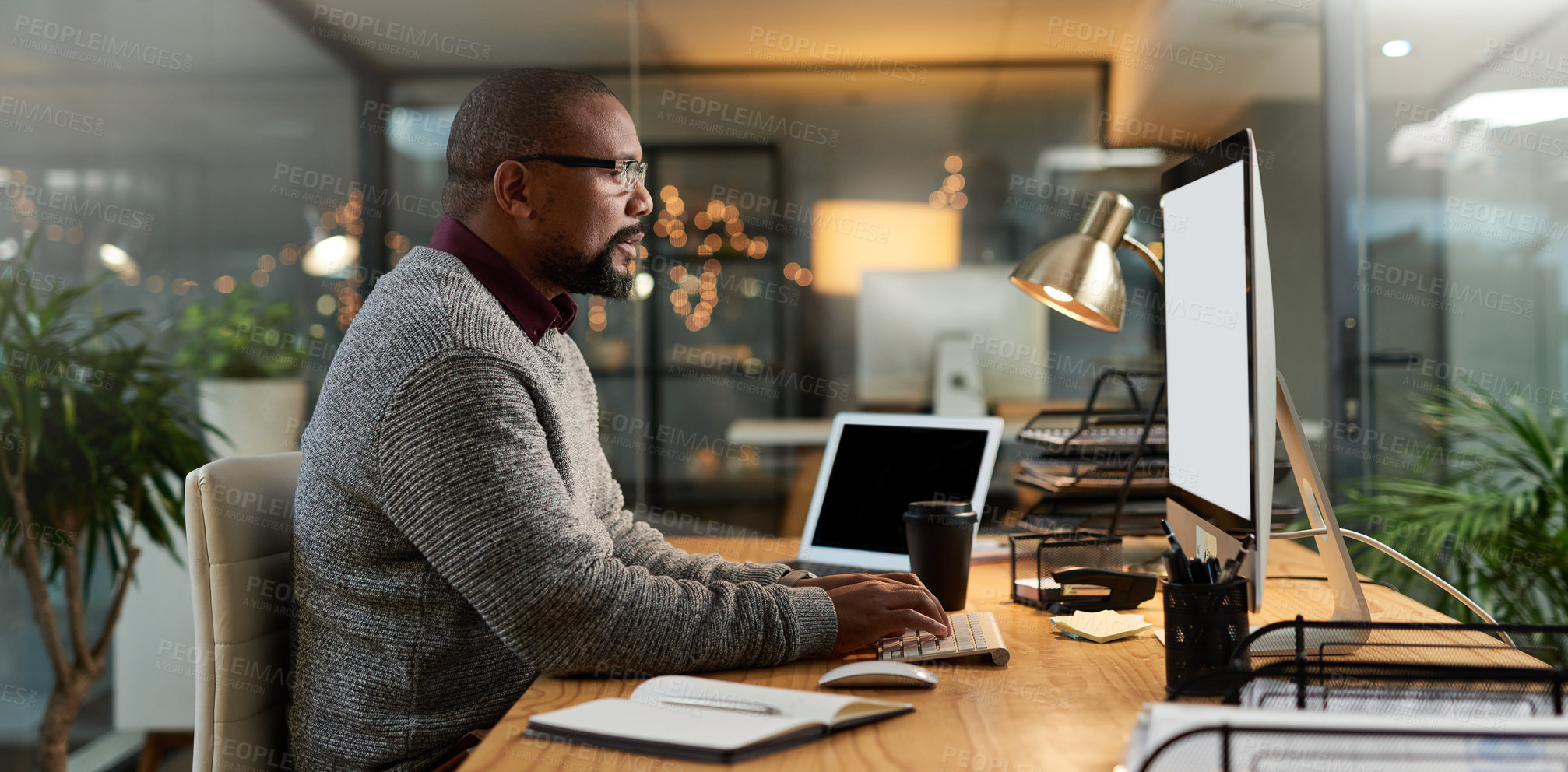 Buy stock photo Cropped shot of a mature businessman sitting alone and working on his computer in his office late at night