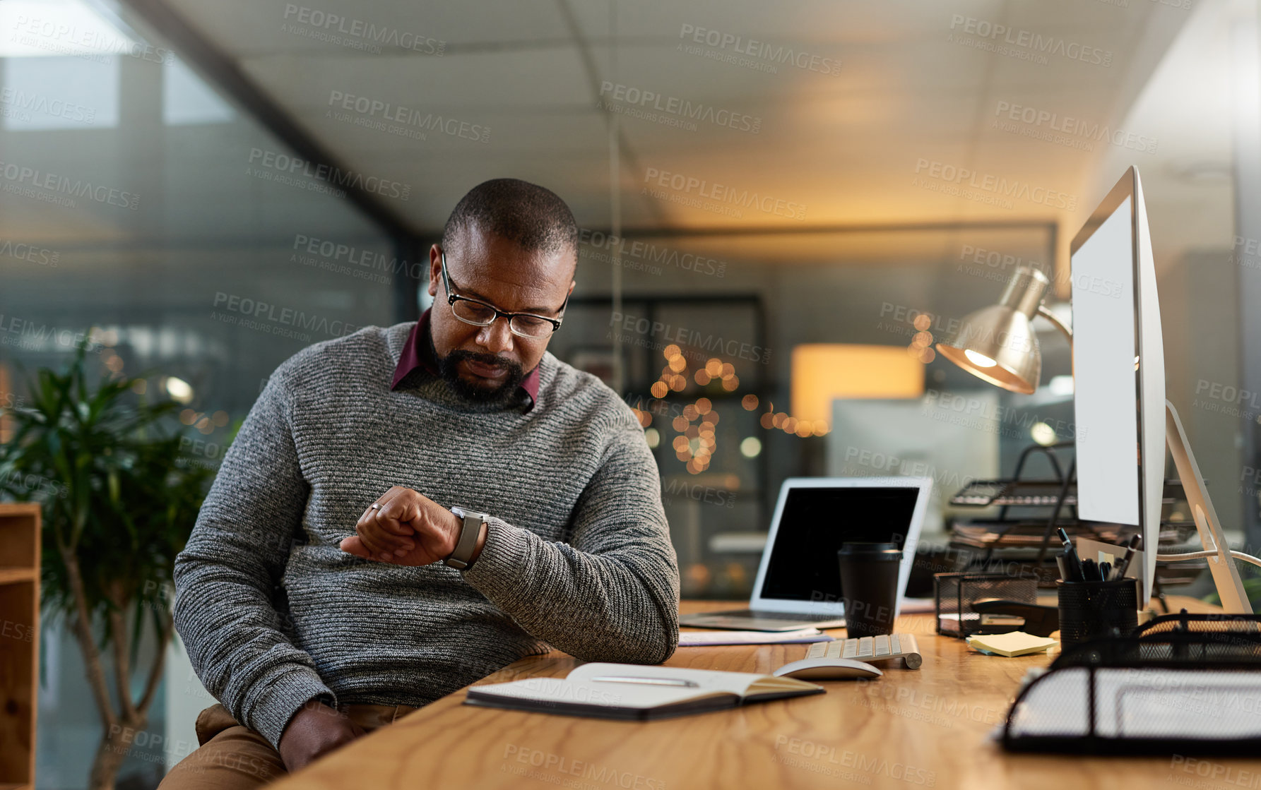 Buy stock photo Cropped shot of a handsome mature businessman sitting at his office desk and checking his watch during a late shift