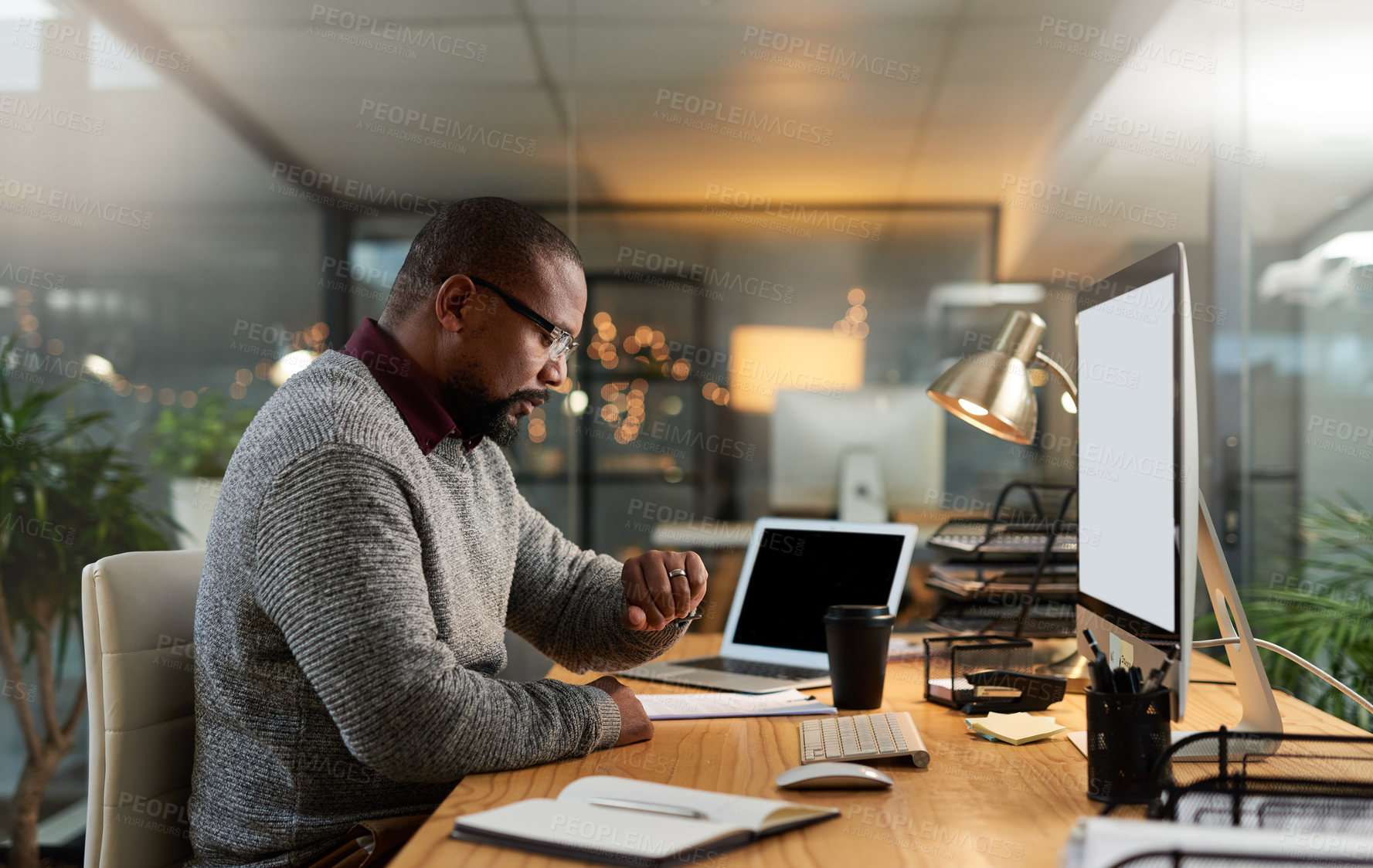 Buy stock photo Cropped shot of a handsome mature businessman sitting at his office desk and checking his watch during a late shift