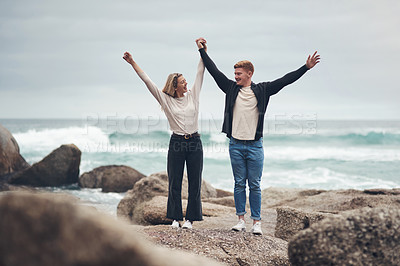 Buy stock photo Shot of a couple looking cheerful while spending time together at the beach