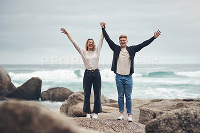 Buy stock photo Shot of a couple looking cheerful while spending time together at the beach