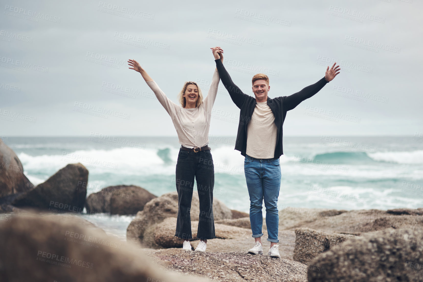 Buy stock photo Shot of a couple looking cheerful while spending time together at the beach