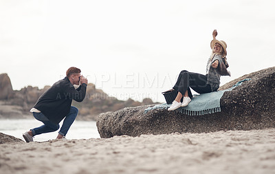 Buy stock photo Shot of a man taking pictures of his girlfriend while spending time at the beach