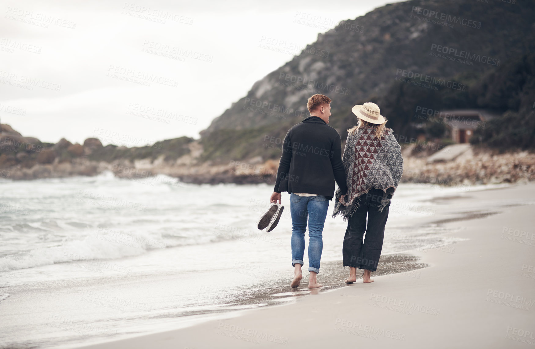 Buy stock photo Shot of a couple holding hands while strolling on the beach