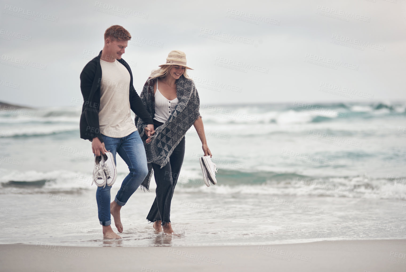 Buy stock photo Shot of a couple holding hands while strolling on the beach