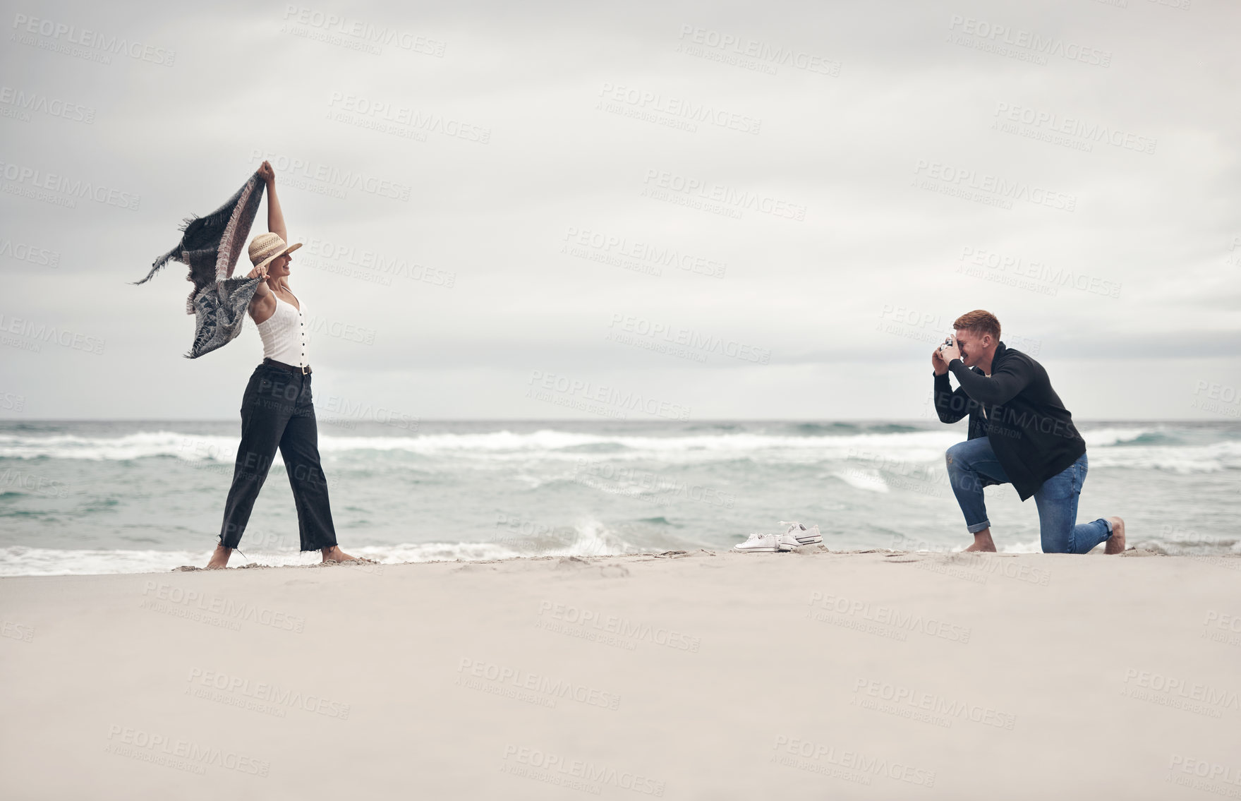 Buy stock photo Shot of a man taking pictures of his girlfriend while spending time at the beach